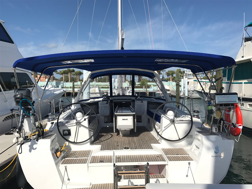 Sailboat cockpit with twin helms beneath a navy Bimini and a clear forward dodger
