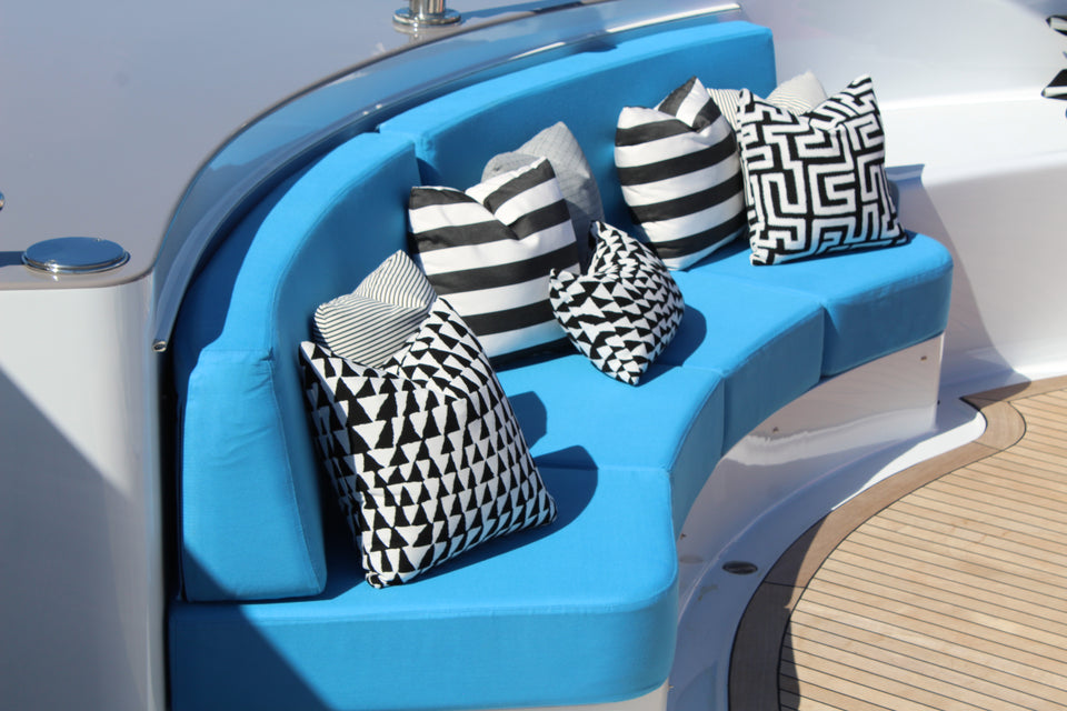 Black and white patterned pillows arranged on curved blue yacht seating