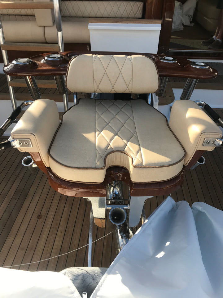 Cream helm chair with diamond-quilted upholstery, wood armrests, and a metal footrest