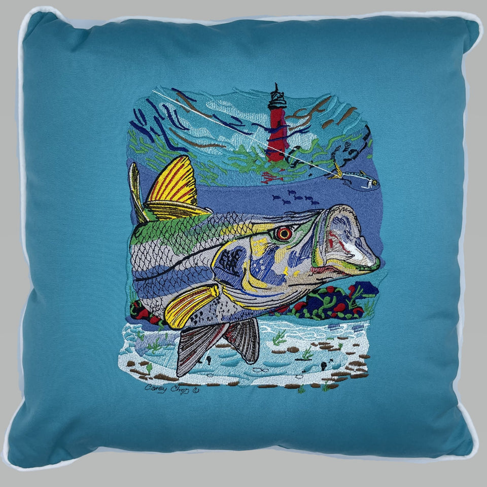 Blue pillow embroidered with colorful fish, a lighthouse and an underwater scene